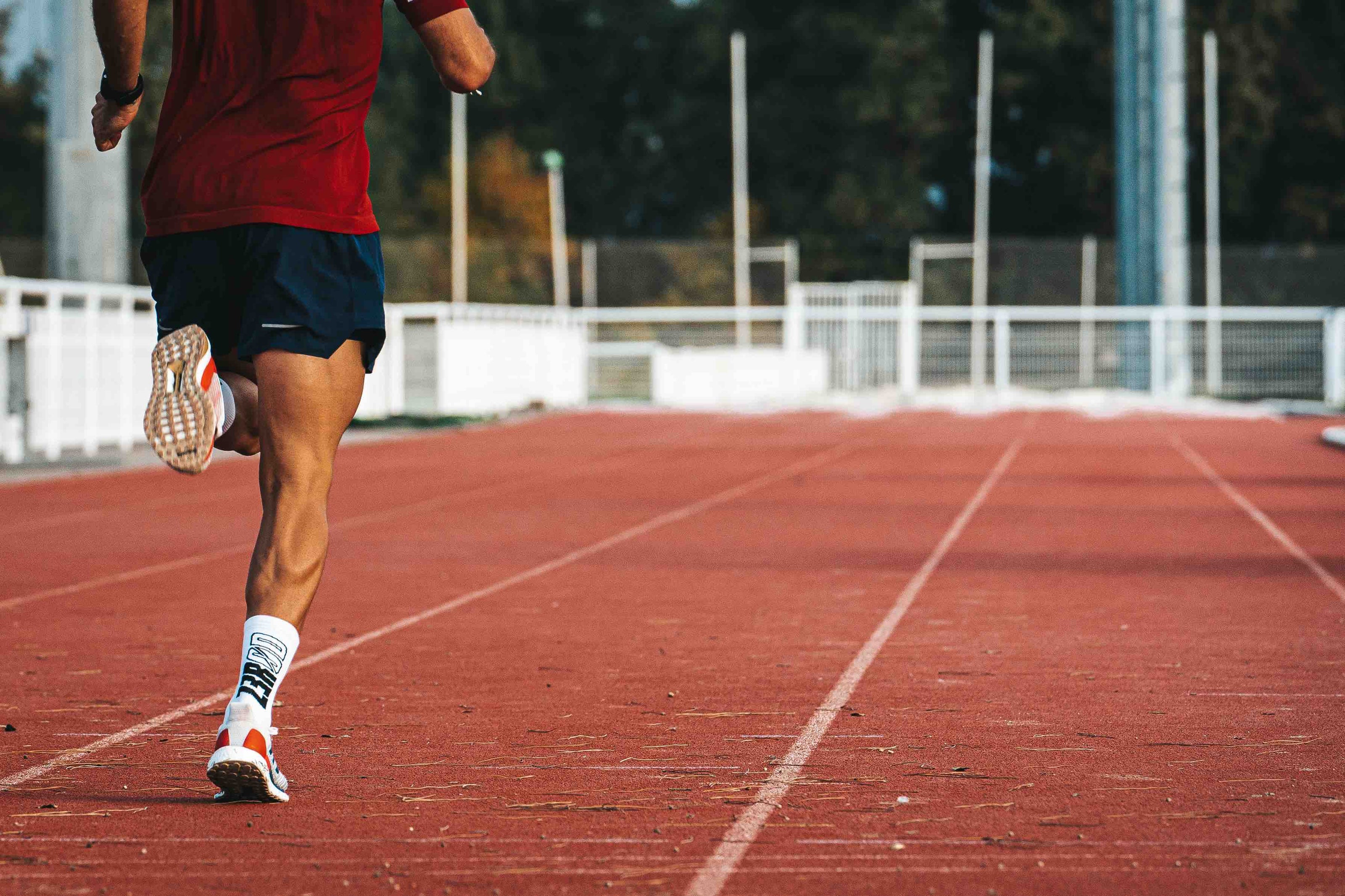 Sportif de dos en train de courir sur une piste d'athlétisme