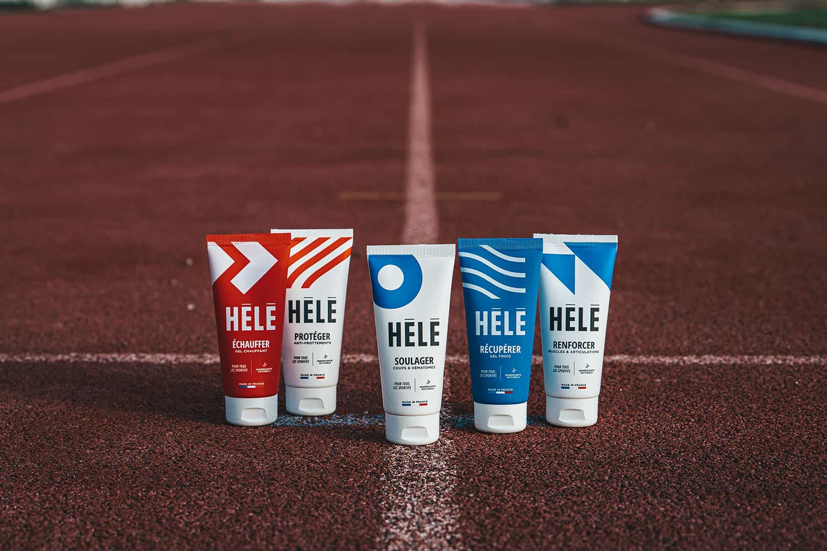 Tubes de produits pour sportifs HELE sur une piste d'athlétisme : gel chaud, gel cryo, gel articulaire et musculaire, gel coups et hématomes, crème anti frottements