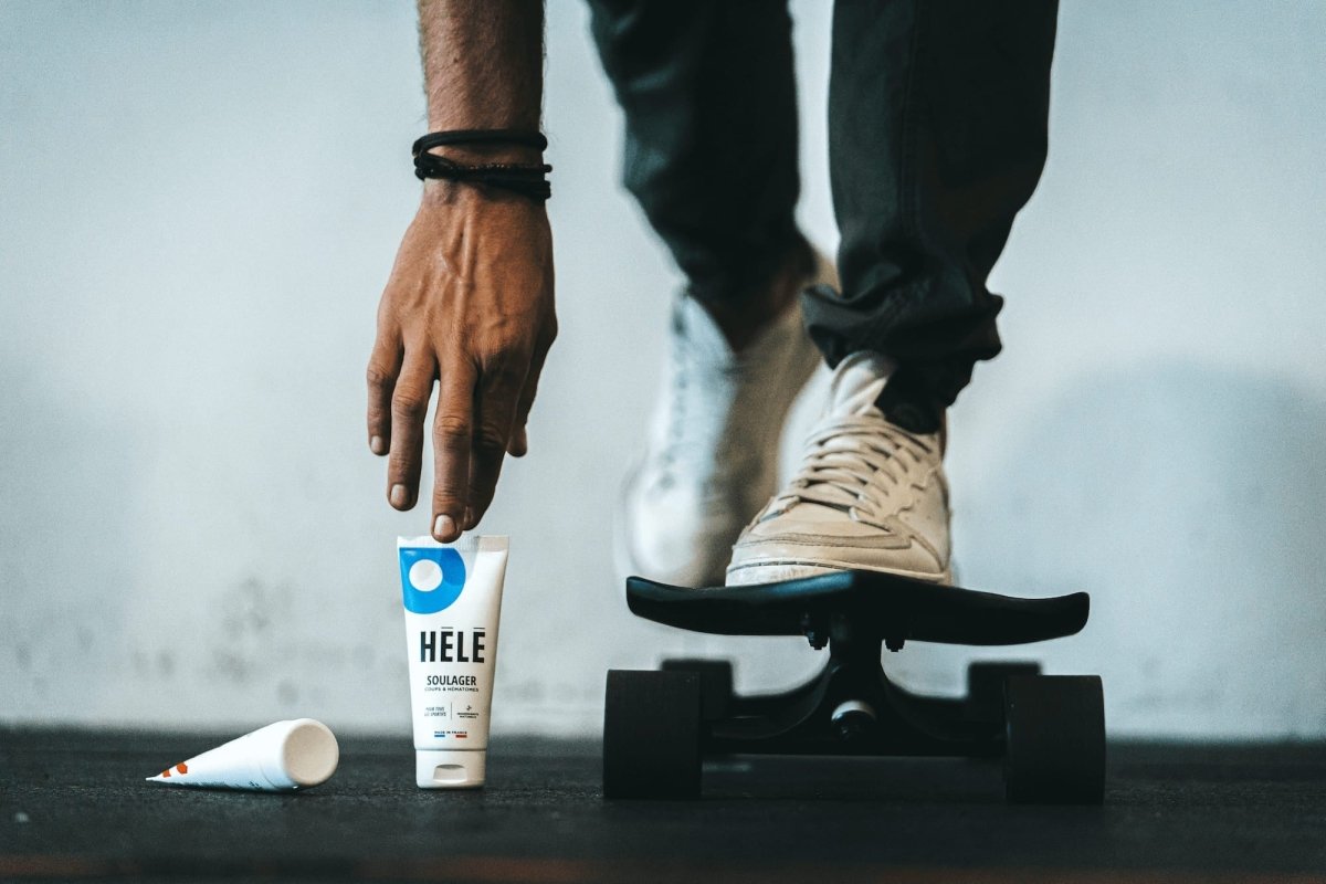 Gros plan sur skateboard et pieds de skateur avec main attrapant un tube de gel coups et hématomes