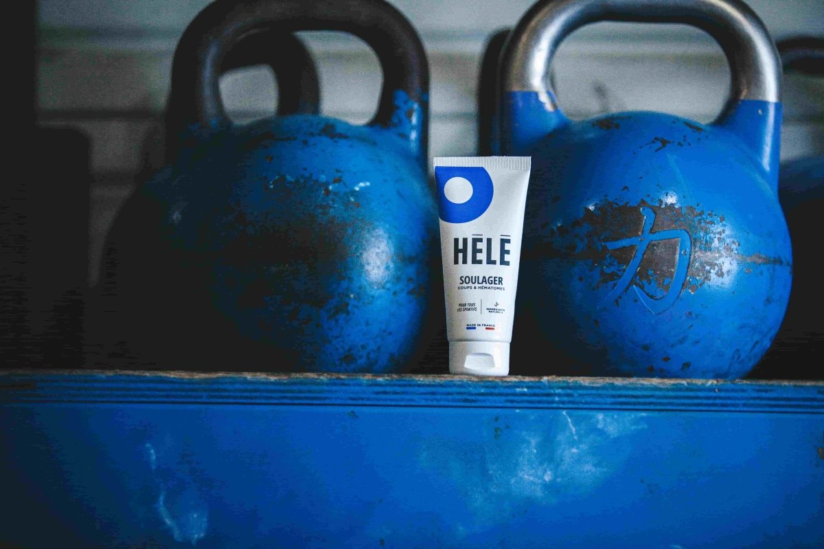 Tube de gel coups et hématomes posé entre deux kettlebells bleus
