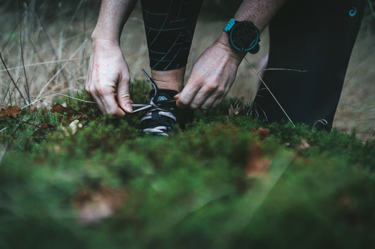 Anti démangeaisons naturels - Femme sportive refaisant ses lacets en forêt