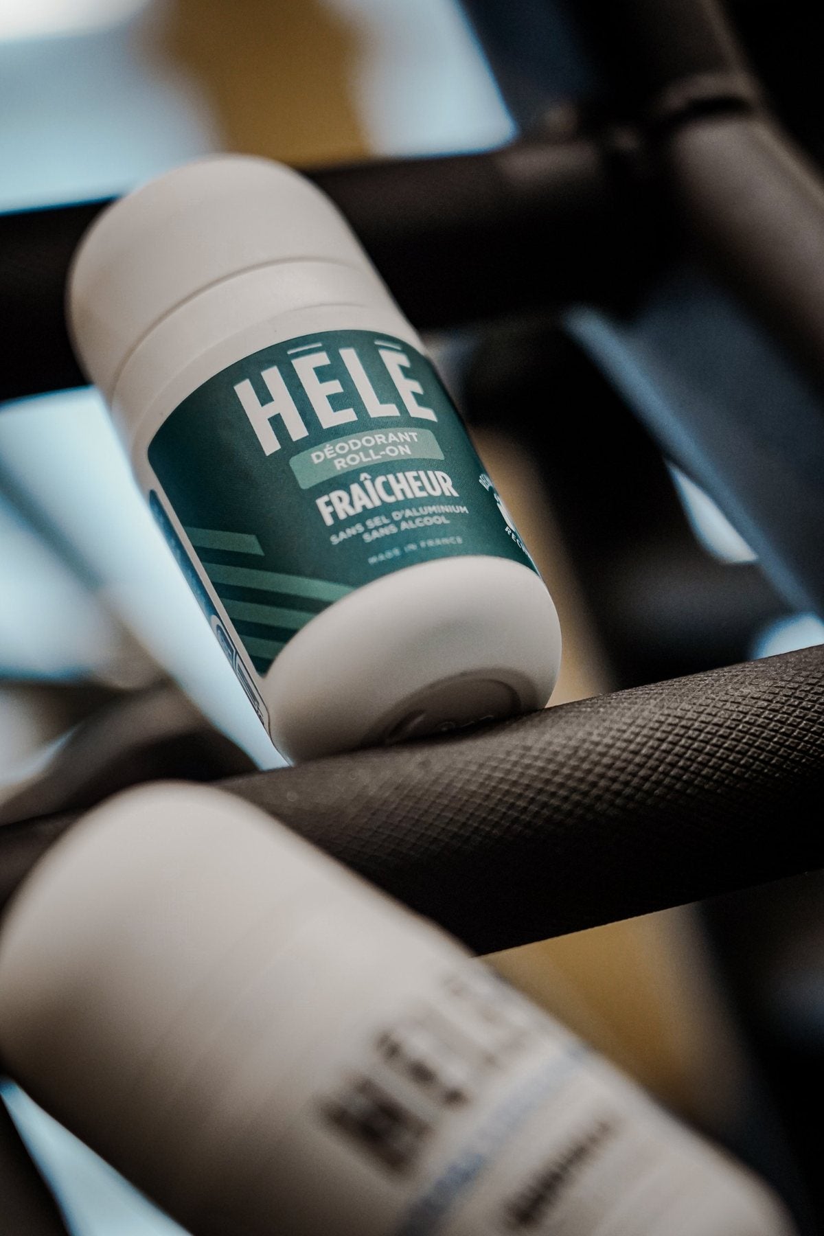 Déodorant roll-on Fraîcheur HELE Sport posé sur une barre en métal texturé