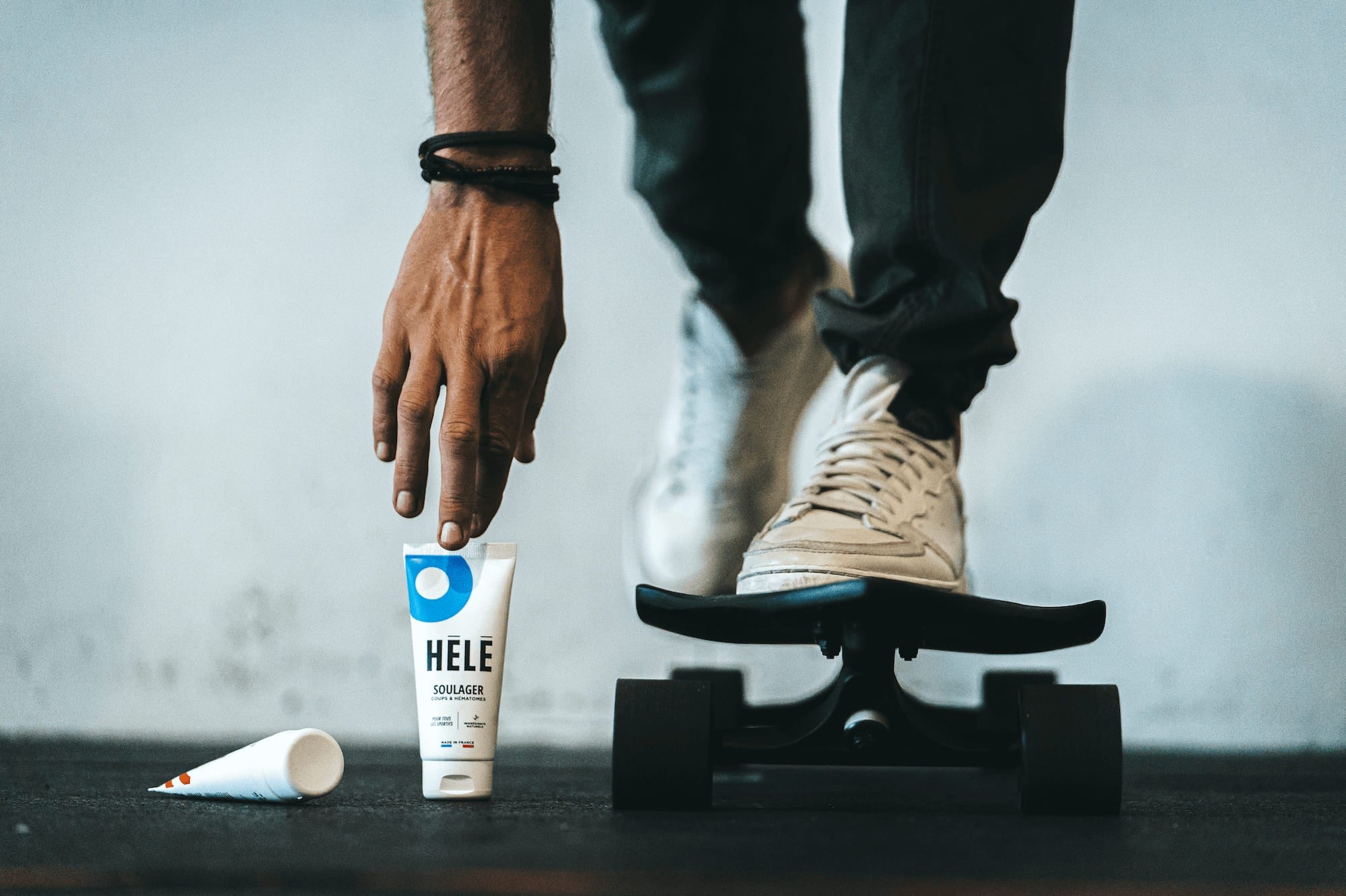 Sportif sur un skate-board en train de ramasser un tube de gel coups et hématomes Soulager de la marque HELE