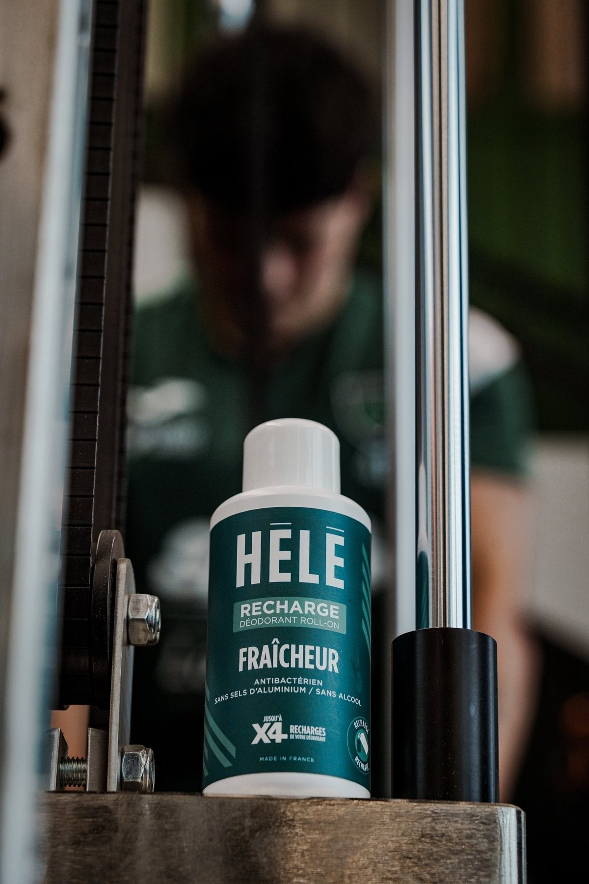 Recharge 200 ml du déodorant roll-on Fraîcheur HELE Sport posée sur un socle devant une machine métallique